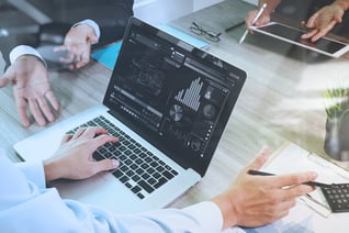 business documents on office table with smart phone and laptop computer and graph financial with social network diagram and three colleagues discussing data in the background-1